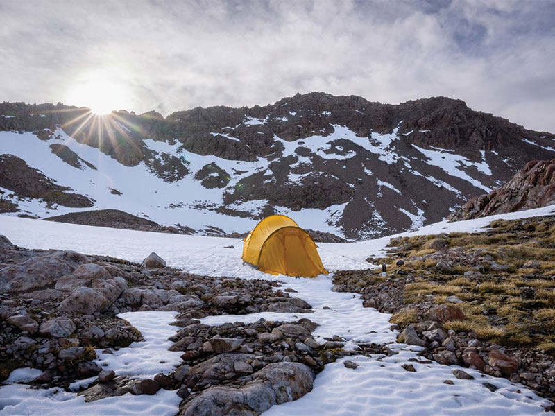 macpac olympus tent in the snow with a sun flare in arthurs pass new zealand